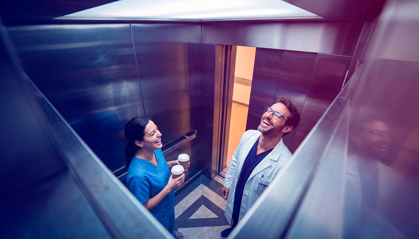 Médica e médico sorrindo no elevador do hospital